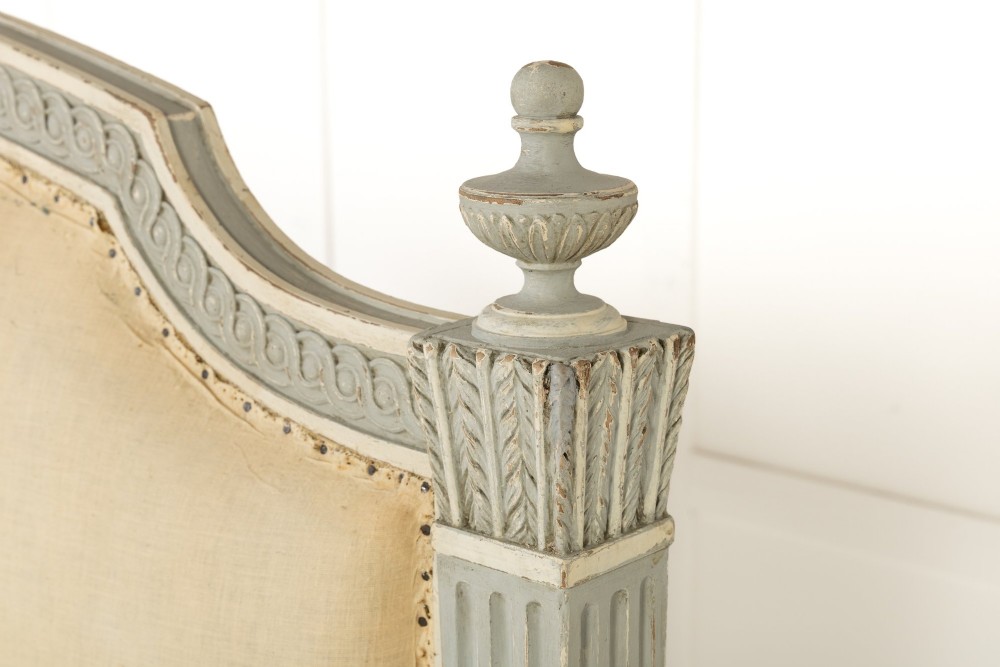 A 19th-century French Neoclassical double bed frame with a light grey painted finish, fluted posts topped with finials, and an arched cream upholstered headboard. View IV