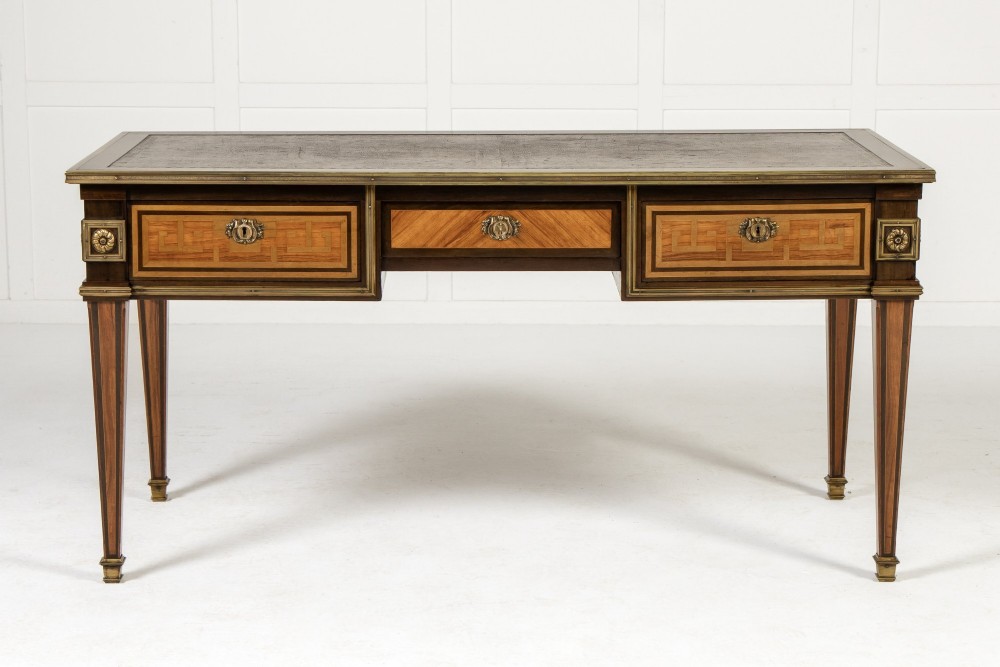 A 19th-century French Louis XVI style bureau plat writing desk featuring geometric parquetry inlay, three frieze drawers, a leather top insert, and brass mounts on square tapered legs. View II