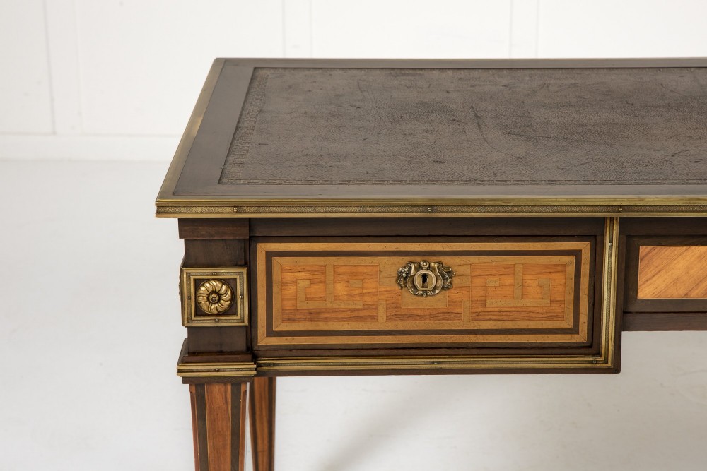 A 19th-century French Louis XVI style bureau plat writing desk featuring geometric parquetry inlay, three frieze drawers, a leather top insert, and brass mounts on square tapered legs. View III
