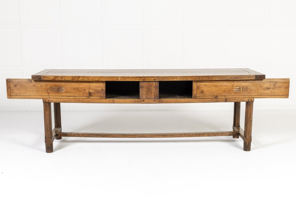A long, rectangular 18th-century French oak table featuring two drawers with carved recessed pulls and lower stretchers connecting the legs. View III
