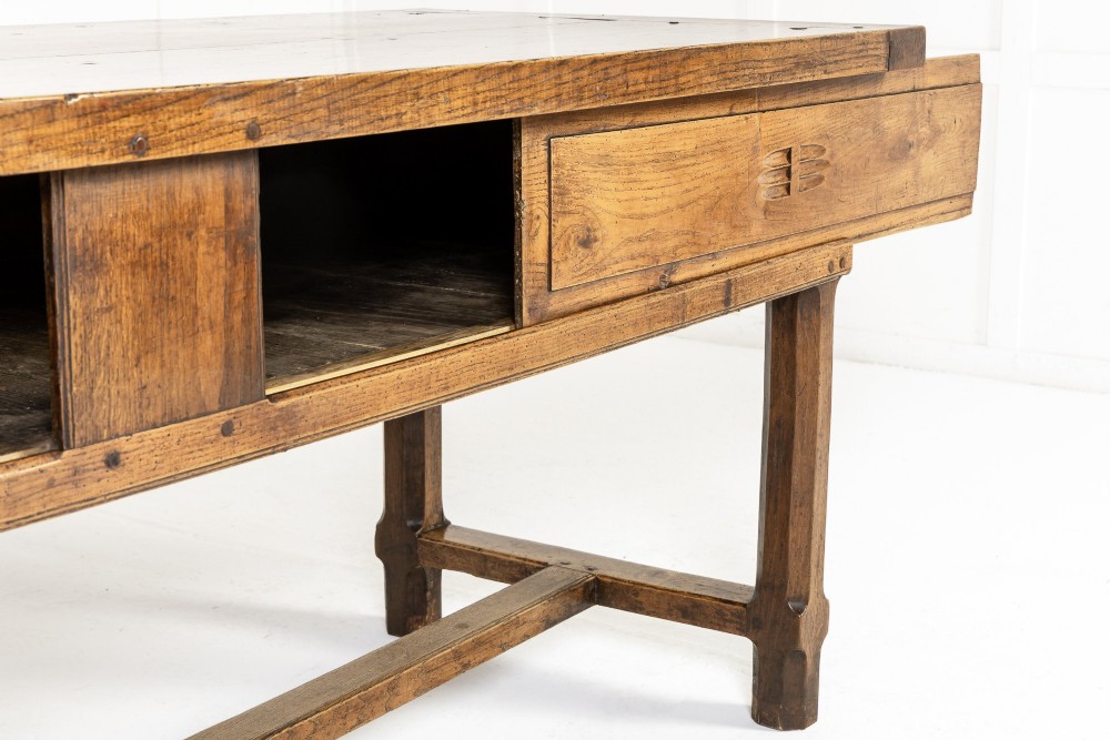 A long, rectangular 18th-century French oak table featuring two drawers with carved recessed pulls and lower stretchers connecting the legs. View V
