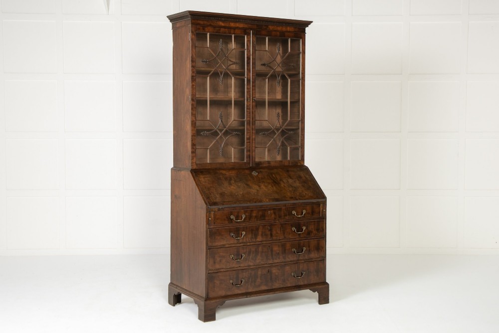 An 18th-century Georgian mahogany bureau bookcase featuring a twin-door upper cabinet with astragal glazing bars over a slant-front writing slope and four graduated drawers on bracket feet.