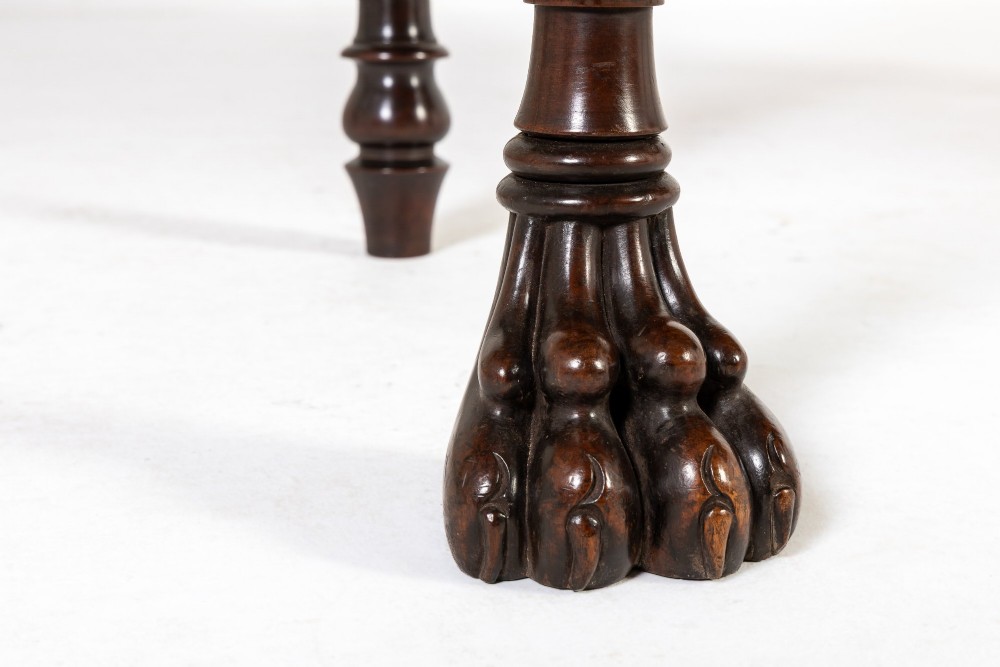 A 19th-century Regency mahogany serving table featuring a pointed splashback upstand, decorative carved frieze, turned front legs, and carved lion paw feet. View V