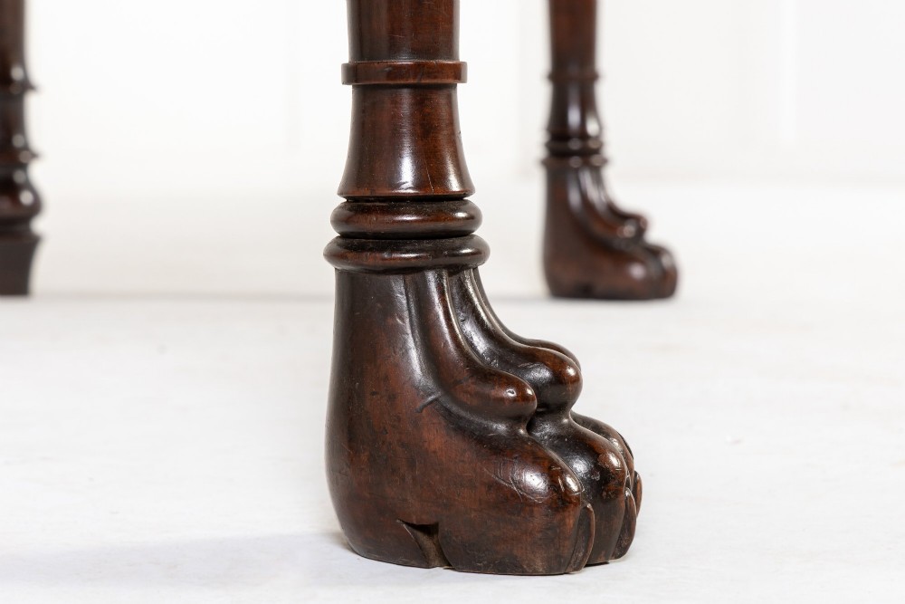 A 19th-century Regency mahogany serving table featuring a pointed splashback upstand, decorative carved frieze, turned front legs, and carved lion paw feet. View VII