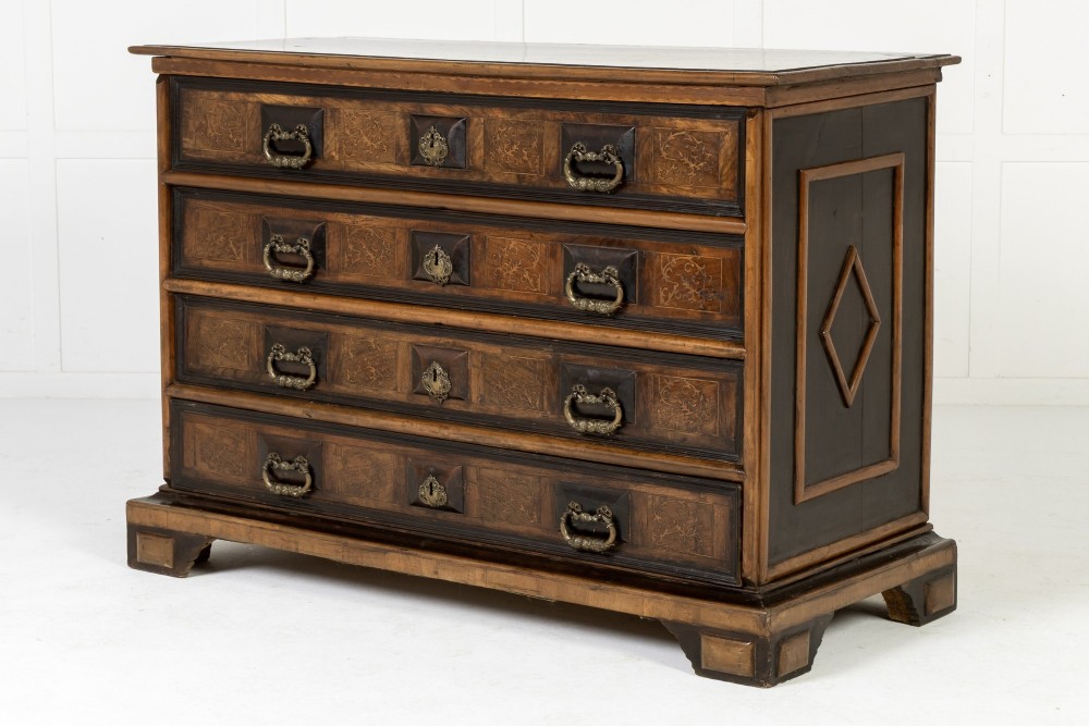 An 18th-century Italian walnut chest of drawers featuring foliage marquetry, brass drop handles, and geometric side moulding. View VI
