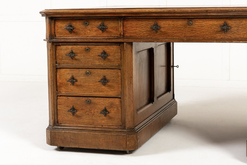 A large 19th-century English oak partners desk with twin pedestals, multiple drawers, metal drop handles, and panelled sides. View II