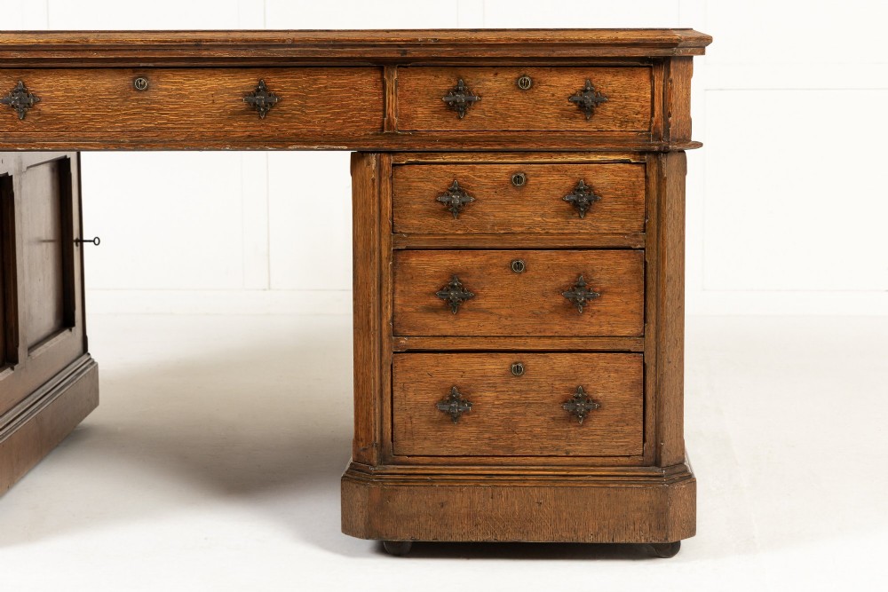 A large 19th-century English oak partners desk with twin pedestals, multiple drawers, metal drop handles, and panelled sides. View III