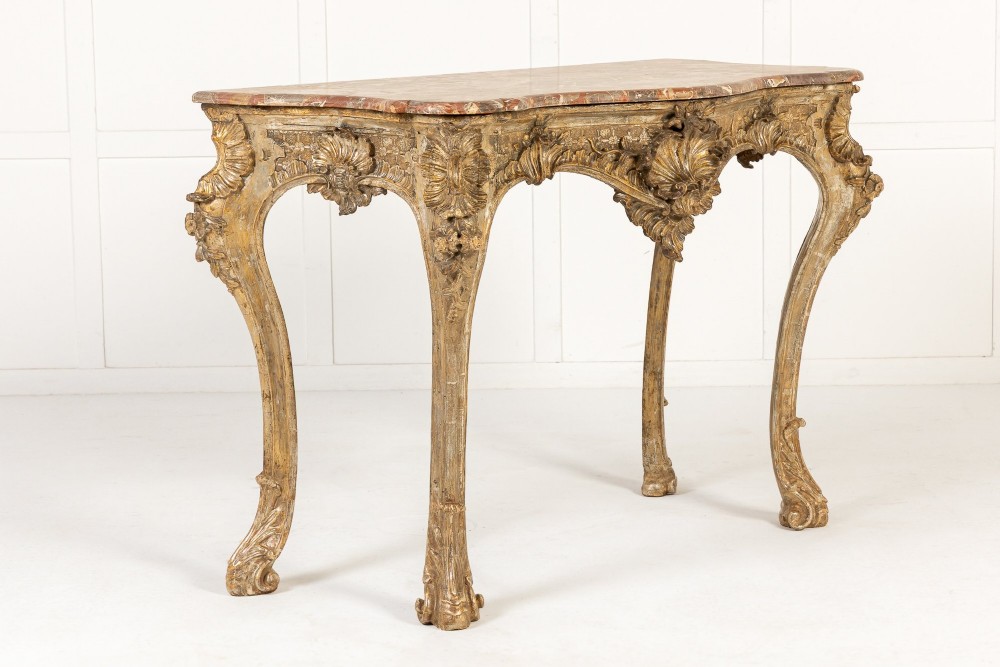 An 18th-century Italian Rococo console table featuring carved silver gilt legs with central shell motifs and a contoured variegated marble top. View X