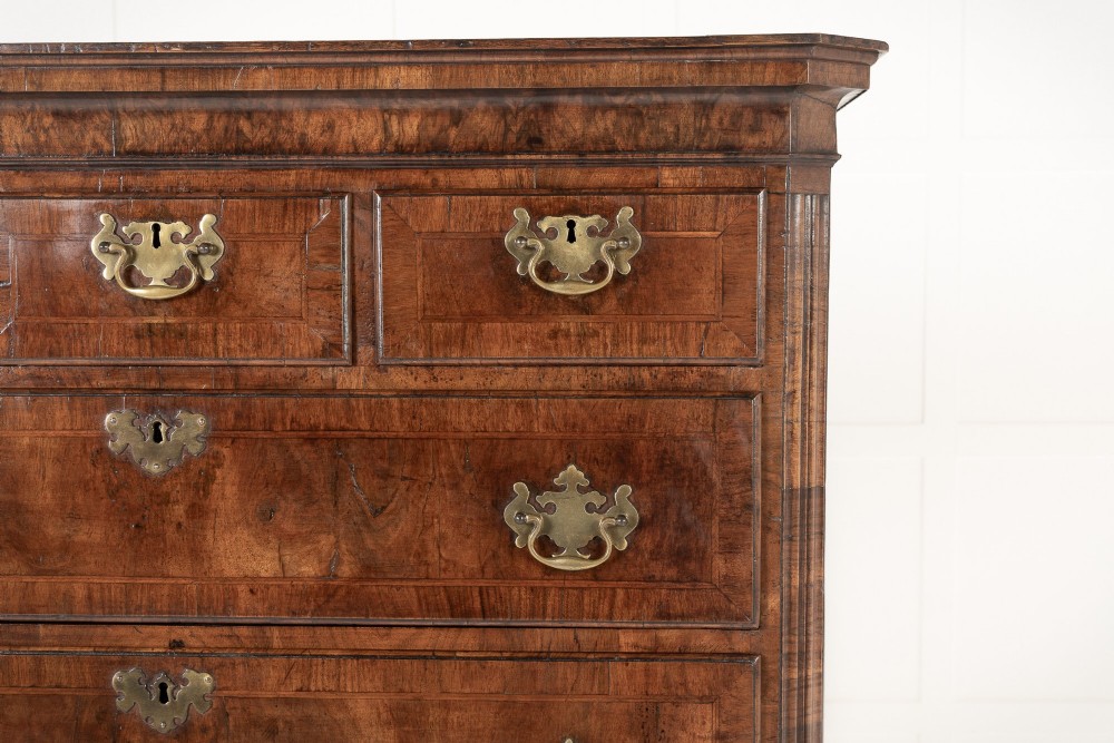 An 18th-century English walnut chest on chest featuring stacked drawers, figured timber veneers, brass backplate handles, and bracket feet. View III