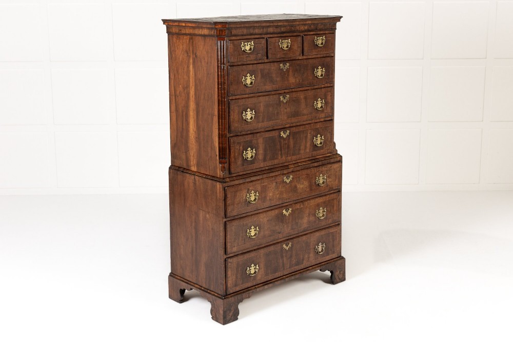 An 18th-century English walnut chest on chest featuring stacked drawers, figured timber veneers, brass backplate handles, and bracket feet. View VI