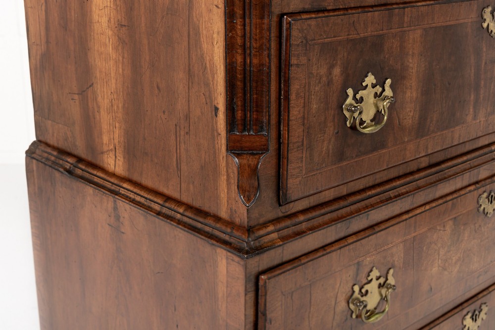 An 18th-century English walnut chest on chest featuring stacked drawers, figured timber veneers, brass backplate handles, and bracket feet. View VII