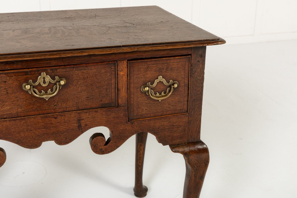 An 18th-century dark oak lowboy table featuring three drawers with brass handles, a shaped apron, and cabriole legs terminating in pad feet. View III