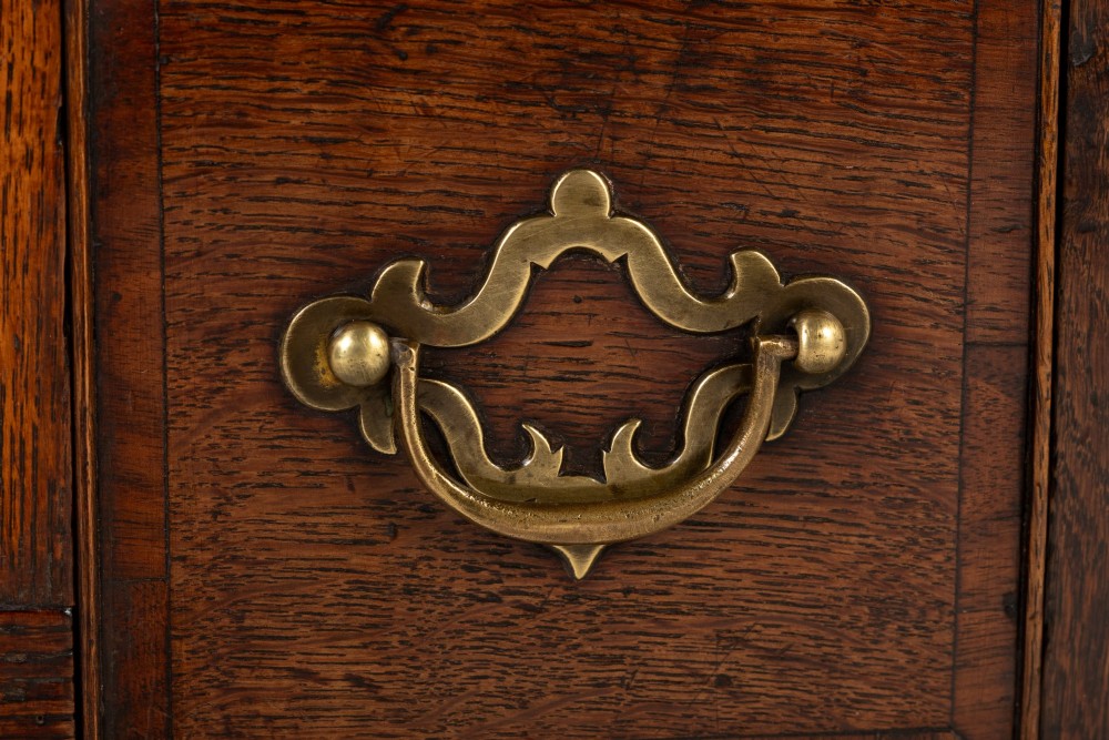 An 18th-century dark oak lowboy table featuring three drawers with brass handles, a shaped apron, and cabriole legs terminating in pad feet. View VI