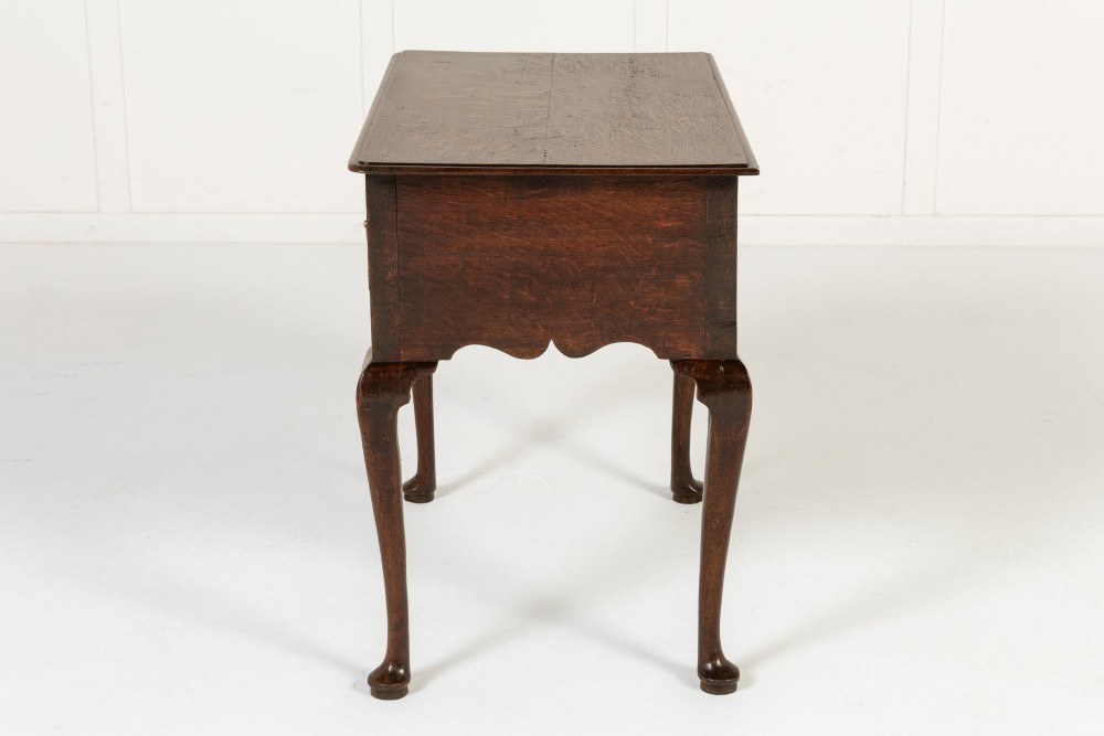 An 18th-century dark oak lowboy table featuring three drawers with brass handles, a shaped apron, and cabriole legs terminating in pad feet. View VII