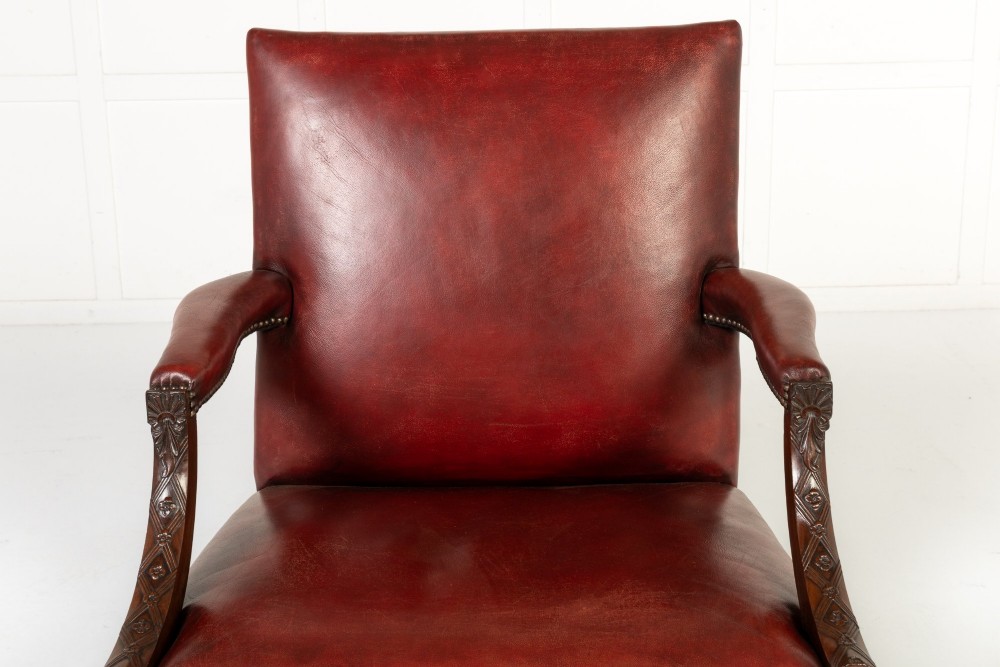An 18th-century English Gainsborough armchair featuring deep red leather upholstery with brass studding, carved mahogany arms, and square legs. View II