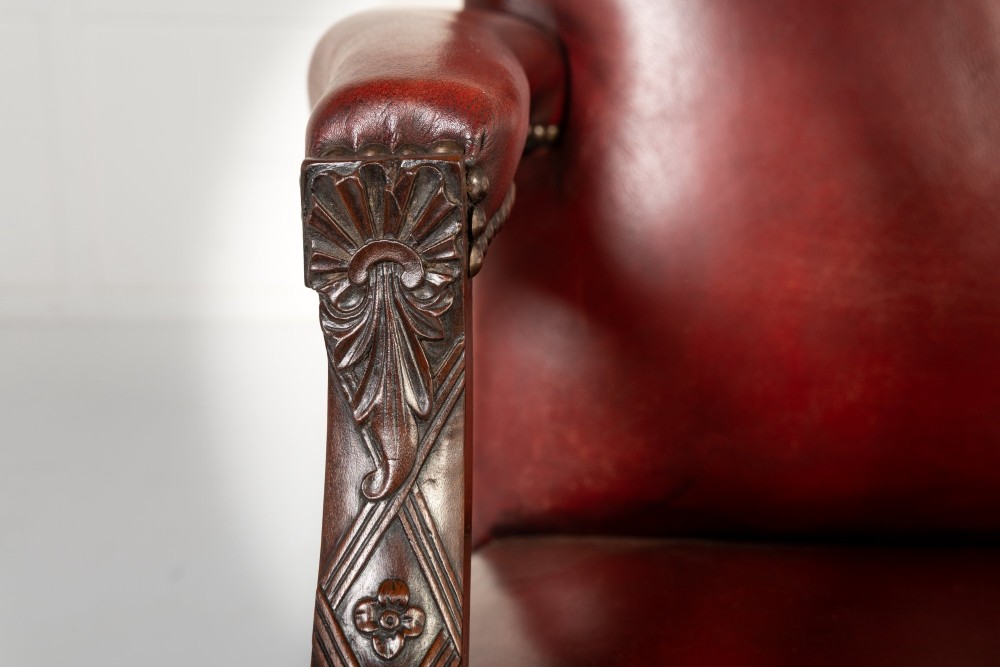 An 18th-century English Gainsborough armchair featuring deep red leather upholstery with brass studding, carved mahogany arms, and square legs. View IV