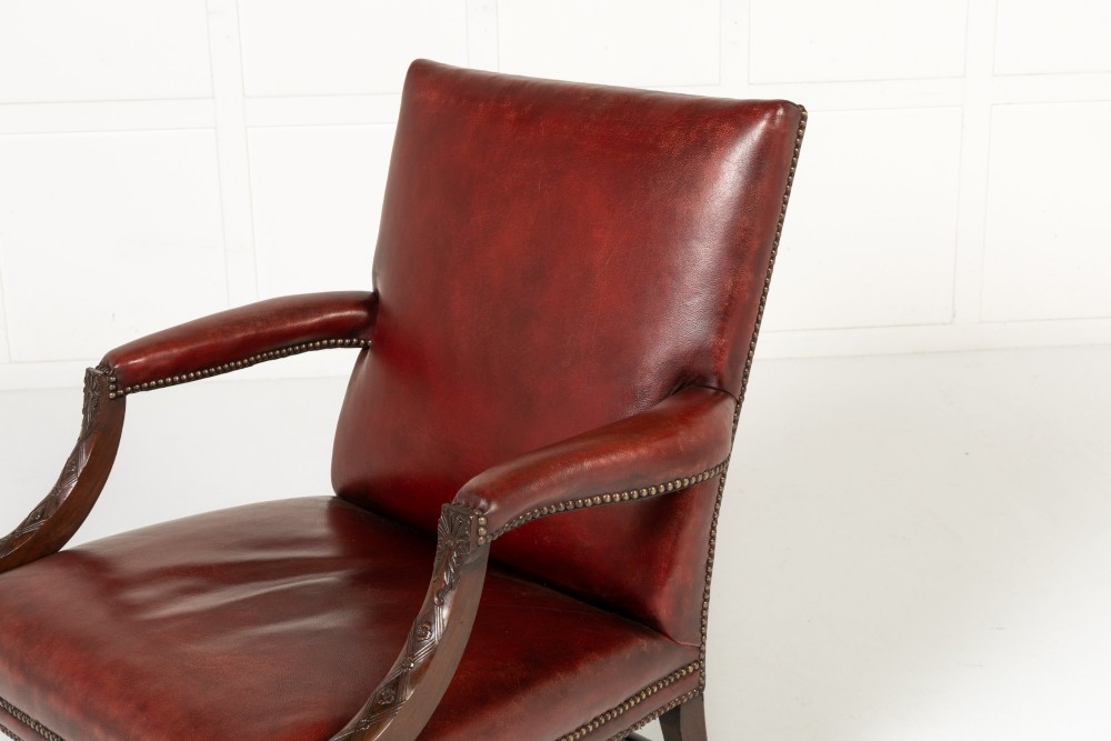 An 18th-century English Gainsborough armchair featuring deep red leather upholstery with brass studding, carved mahogany arms, and square legs. View VII