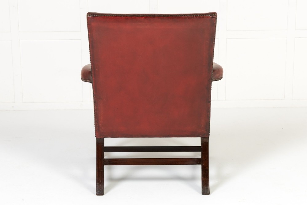 An 18th-century English Gainsborough armchair featuring deep red leather upholstery with brass studding, carved mahogany arms, and square legs. View IX