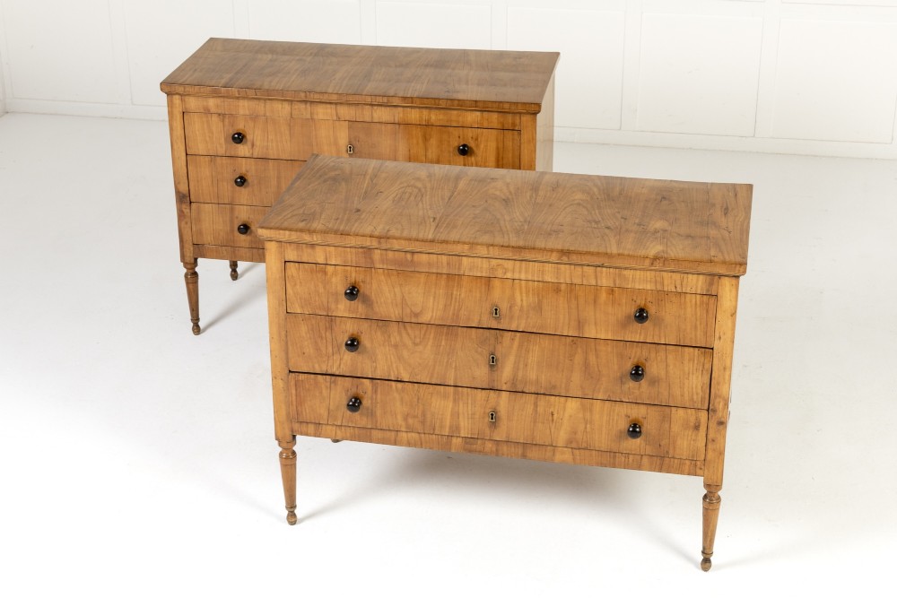 A pair of early 19th-century Italian cherrywood commodes featuring three full-width drawers with dark ebonised knobs and slender turned tapered legs. View II