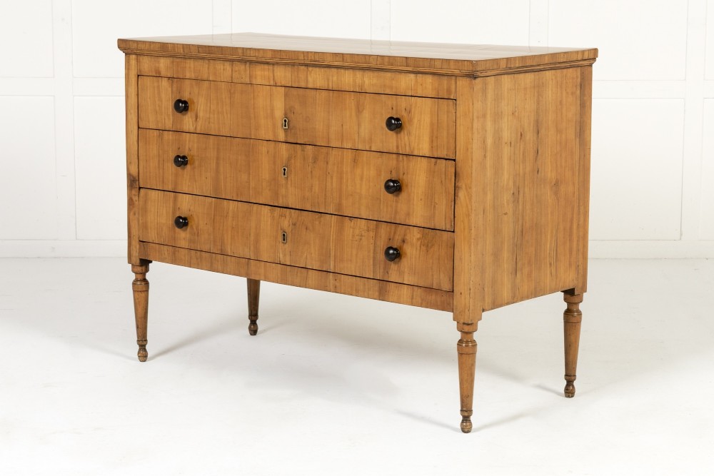 A pair of early 19th-century Italian cherrywood commodes featuring three full-width drawers with dark ebonised knobs and slender turned tapered legs. View III