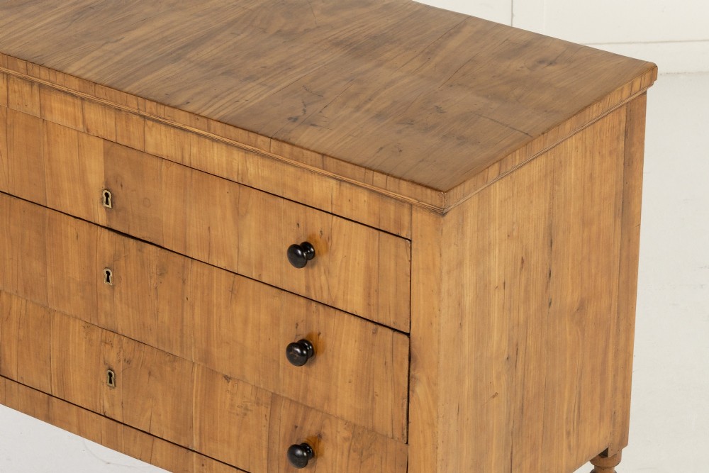 A pair of early 19th-century Italian cherrywood commodes featuring three full-width drawers with dark ebonised knobs and slender turned tapered legs. View IV