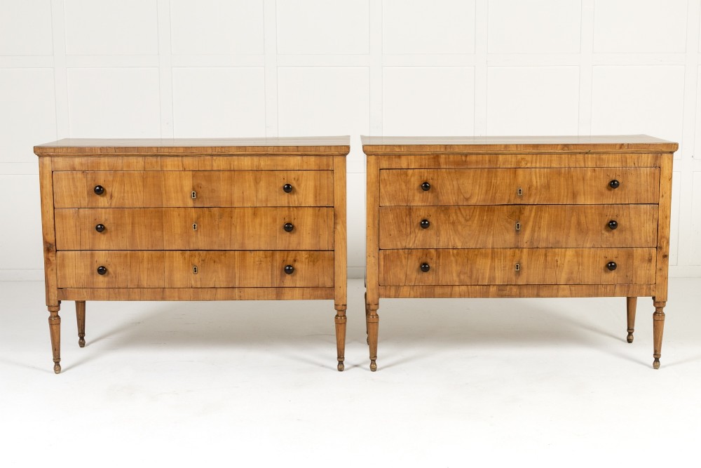 A pair of early 19th-century Italian cherrywood commodes featuring three full-width drawers with dark ebonised knobs and slender turned tapered legs. View VIII