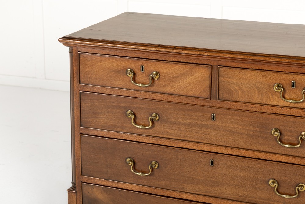 An 18th-century George III mahogany chest of drawers featuring two short over three long graduated drawers with brass swan-neck handles and bracket feet. View II