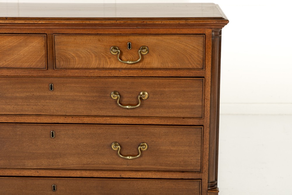 An 18th-century George III mahogany chest of drawers featuring two short over three long graduated drawers with brass swan-neck handles and bracket feet. View III