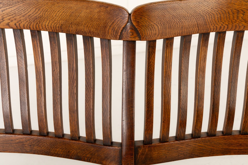 A 19th-century English oak double chair-back settee featuring twin slatted backrests, shaped seats, curved armrests, turned front legs, and splayed rear legs. View III