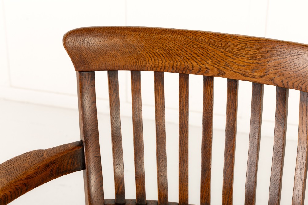 A 19th-century English oak double chair-back settee featuring twin slatted backrests, shaped seats, curved armrests, turned front legs, and splayed rear legs. View VI
