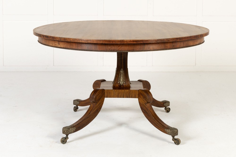A nineteenth-century Regency circular centre table made of rosewood with a quadripod pedestal base on brass castors. View II