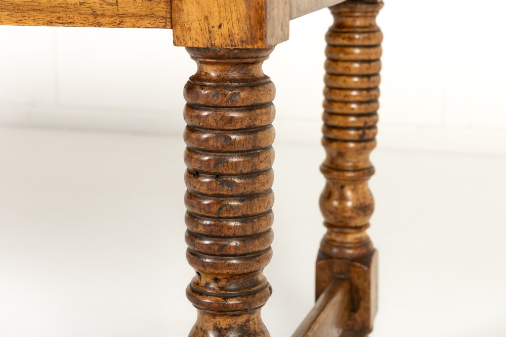 A 19th-century French walnut drapers table with three drawers, wooden knobs, a central keyhole, and turned legs with lower stretchers. View VI