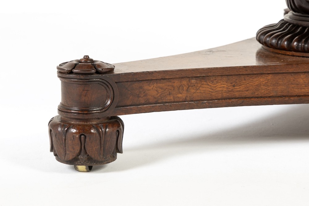An early nineteenth-century circular centre table featuring a figured burr oak top mounted on a carved central column and a tri-form base with carved feet. View V