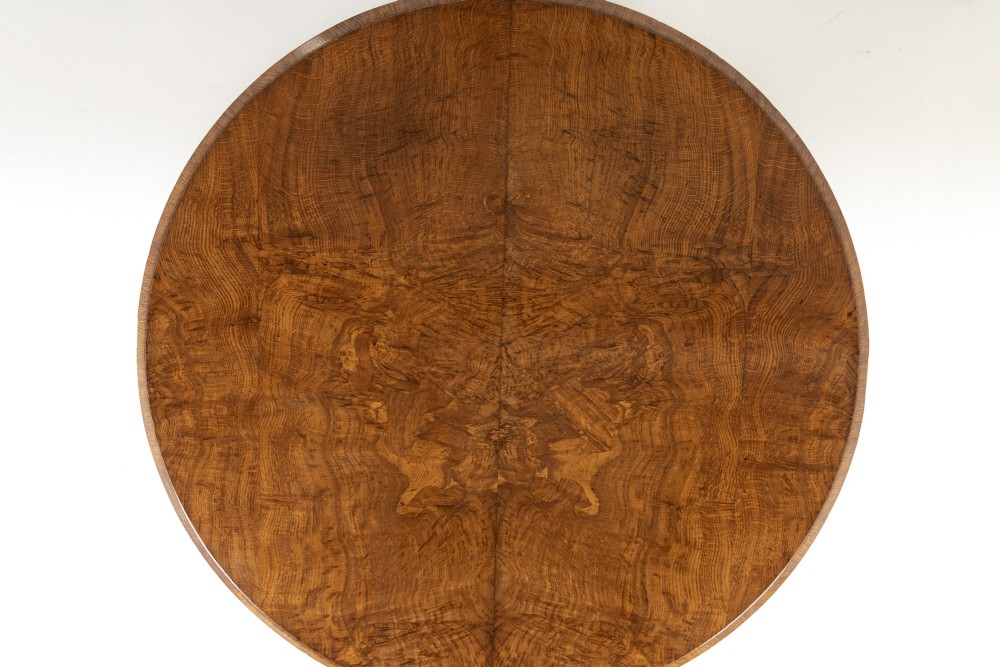 An early nineteenth-century circular centre table featuring a figured burr oak top mounted on a carved central column and a tri-form base with carved feet. View VII