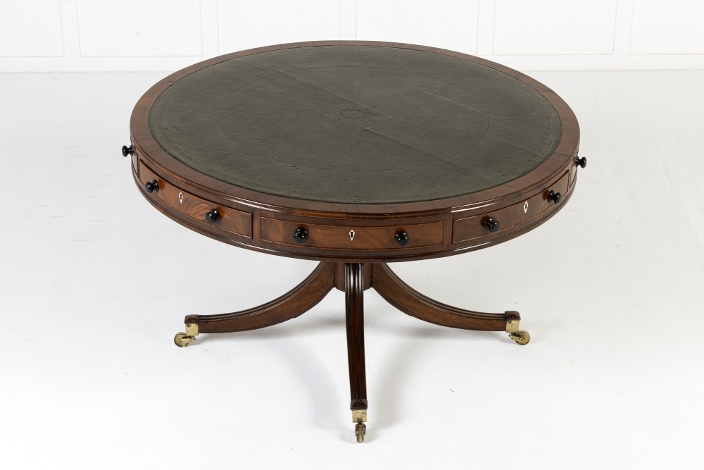 A large 19th-century circular mahogany drum table featuring a green leather top, frieze drawers around the apron, and a central pedestal resting on four splayed legs with brass castors.