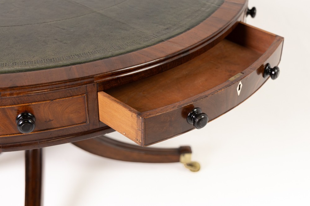 A large 19th-century circular mahogany drum table featuring a green leather top, frieze drawers around the apron, and a central pedestal resting on four splayed legs with brass castors. View IV