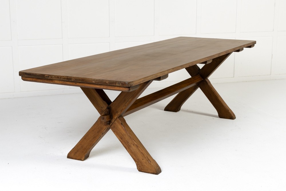 An English pine refectory dining table featuring a rectangular plank top resting on an X-frame trestle base with a central stretcher.