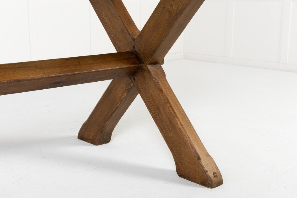 An English pine refectory dining table featuring a rectangular plank top resting on an X-frame trestle base with a central stretcher. View VI