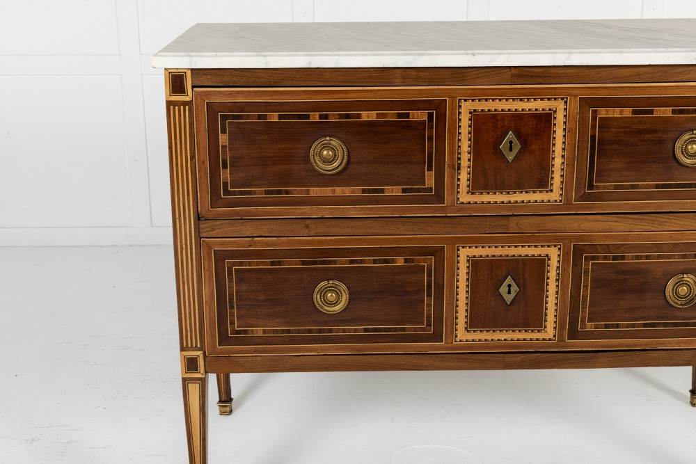 A pair of 18th-century Italian Neoclassical chests of drawers featuring geometric wood inlays, brass ring handles, light marble tops, and tapered square legs. View VII