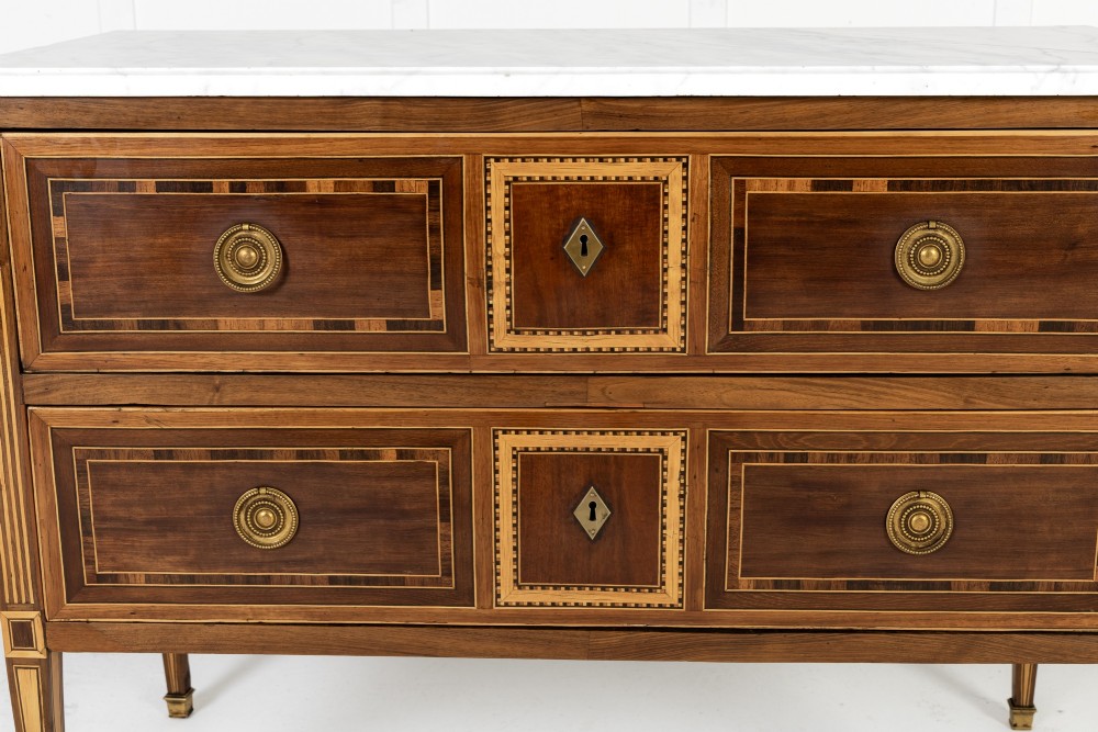 A pair of 18th-century Italian Neoclassical chests of drawers featuring geometric wood inlays, brass ring handles, light marble tops, and tapered square legs. View VIII