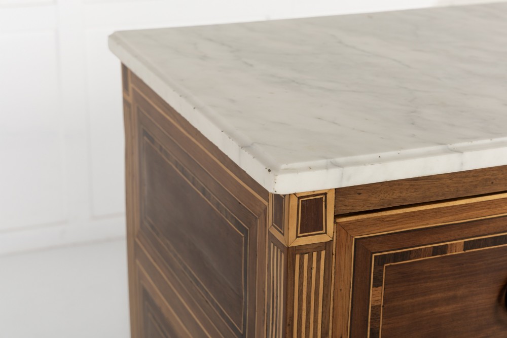 A pair of 18th-century Italian Neoclassical chests of drawers featuring geometric wood inlays, brass ring handles, light marble tops, and tapered square legs. View IX