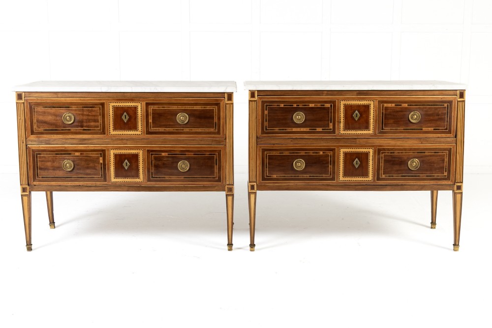 A pair of 18th-century Italian Neoclassical chests of drawers featuring geometric wood inlays, brass ring handles, light marble tops, and tapered square legs. View XII