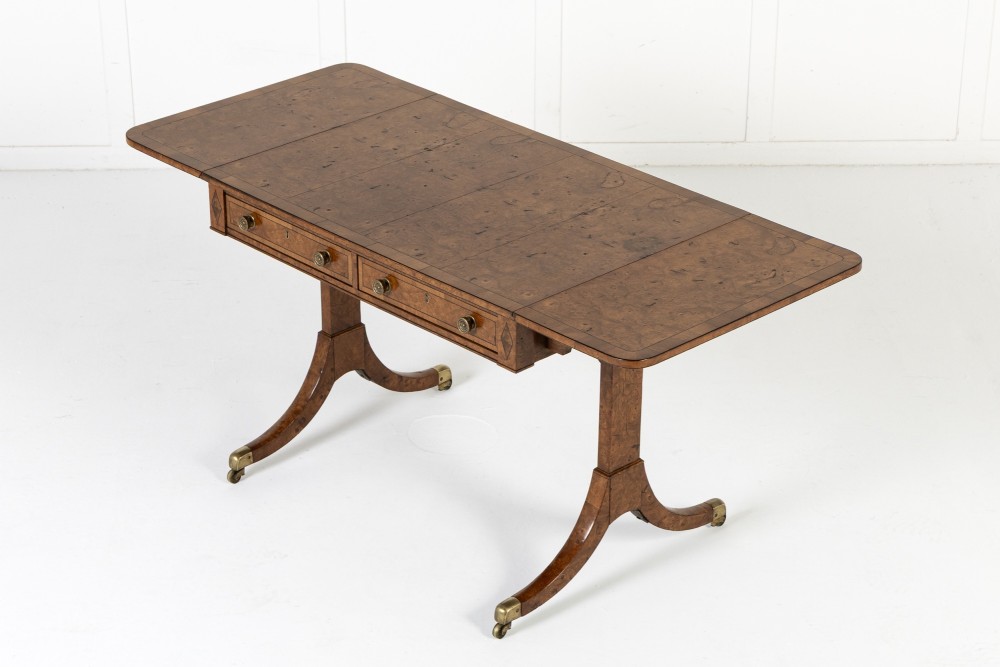 A 19th-century warm brown elm sofa table with two drop leaves, two frieze drawers, twin pedestal supports, and brass castors. View II