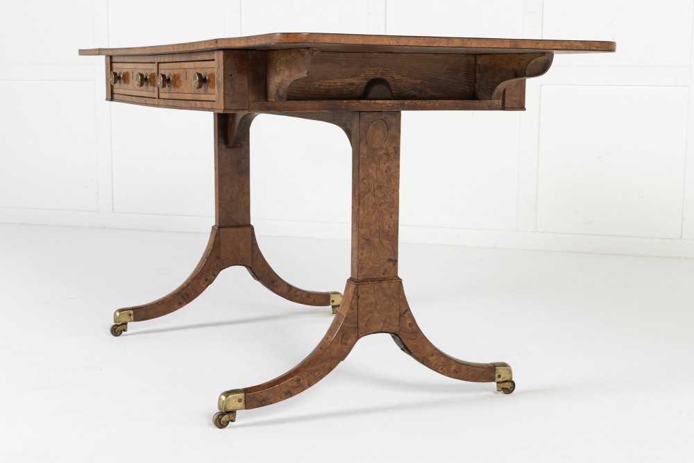 A 19th-century warm brown elm sofa table with two drop leaves, two frieze drawers, twin pedestal supports, and brass castors. View III