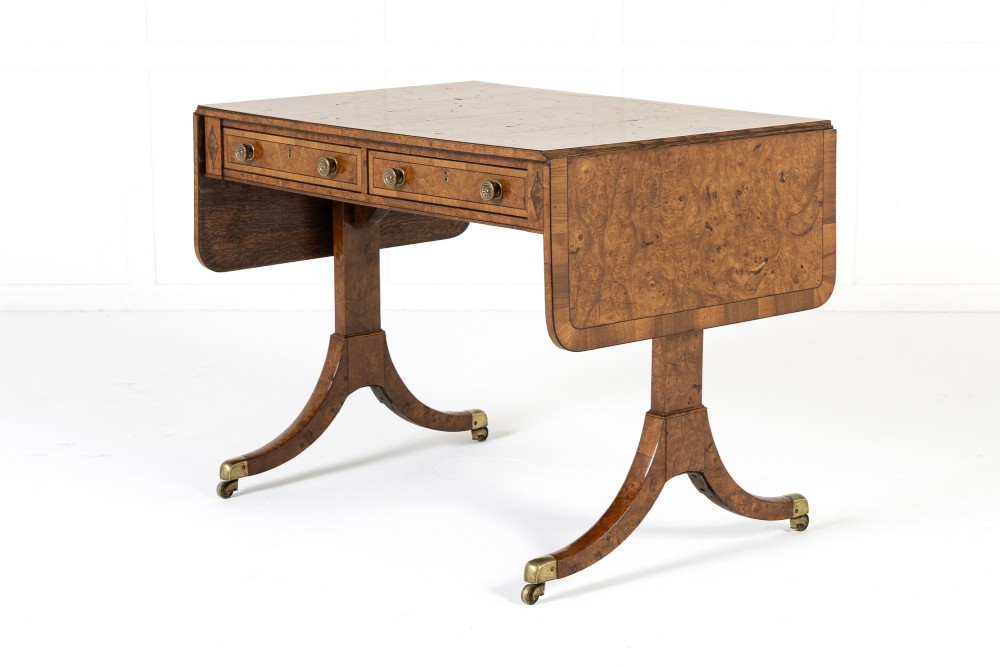 A 19th-century warm brown elm sofa table with two drop leaves, two frieze drawers, twin pedestal supports, and brass castors. View IX