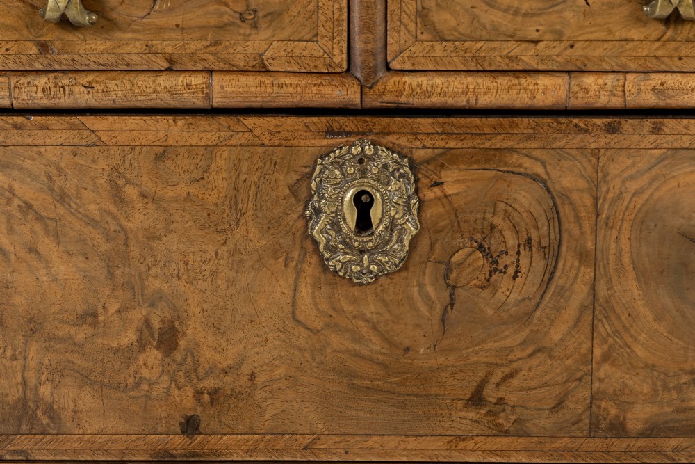 An 18th-century English burr walnut chest of drawers featuring two short over three long drawers with brass drop handles and turned bun feet. View VI