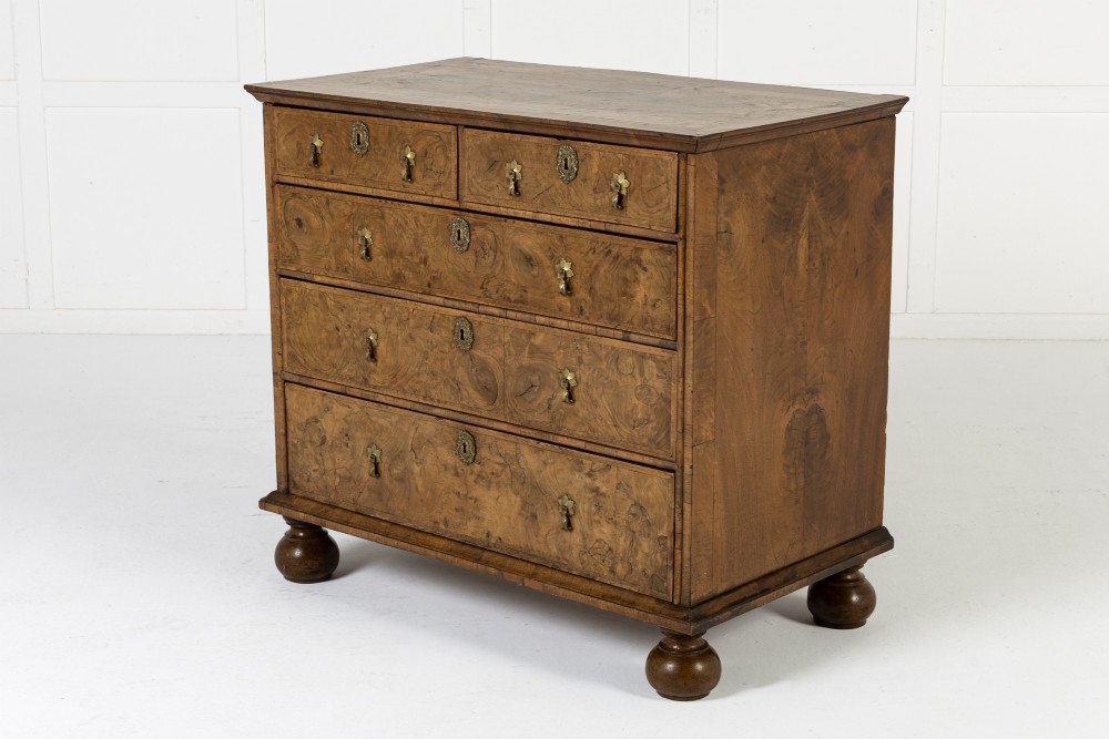 An 18th-century English burr walnut chest of drawers featuring two short over three long drawers with brass drop handles and turned bun feet. View VII
