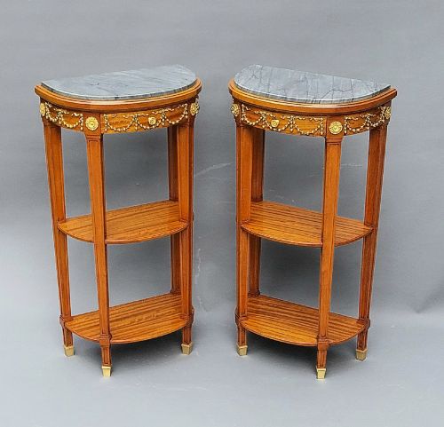 fig 1. A pair of semi-circular French satinwood etagere tables featuring grey marble tops, gilt bronze garland mounts, and two lower tiers.