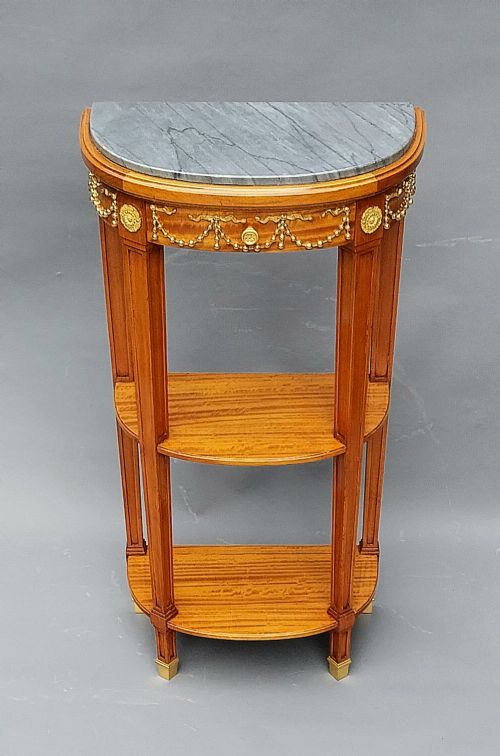 A pair of semi-circular French satinwood etagere tables featuring grey marble tops, gilt bronze garland mounts, and two lower tiers. View VII