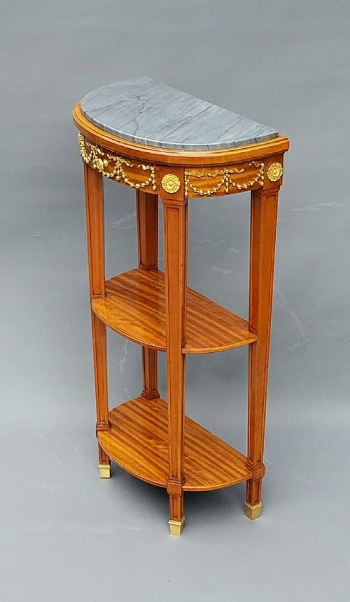 A pair of semi-circular French satinwood etagere tables featuring grey marble tops, gilt bronze garland mounts, and two lower tiers. View VIII